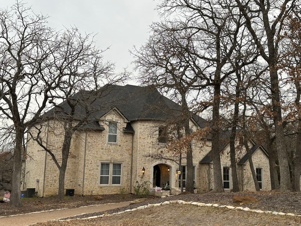 Stone house surrounded by bare trees, featuring a distinctive architecture and rustic charm.