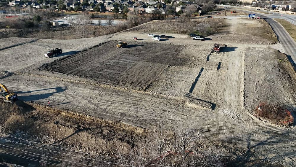 Construction site preparation with heavy machinery and trucks on cleared land.